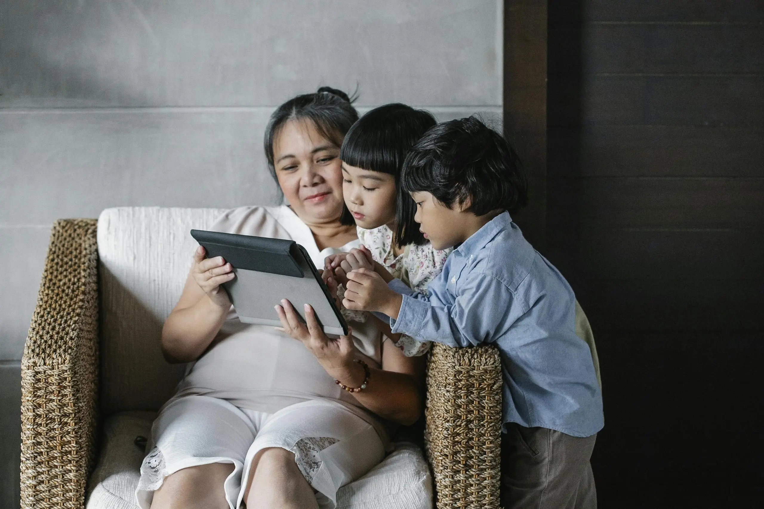 An Asian grandmother spending quality time with her grandchildren, sharing a moment on a tablet.